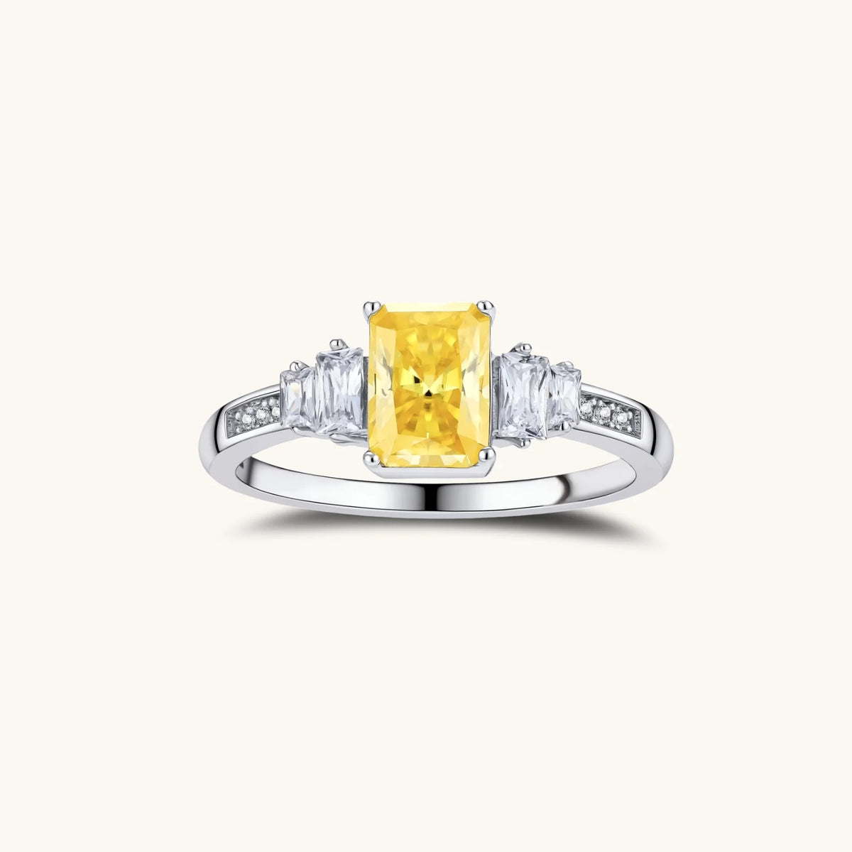 Sterling silver ring with emerald-cut yellow moissanite center stone and clear baguette side stones in elegant setting