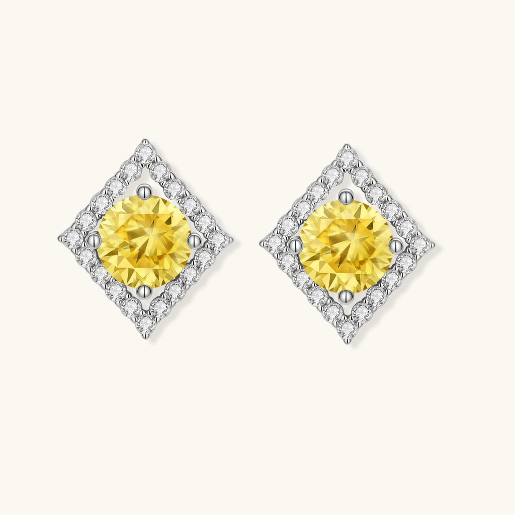 Close-up of diamond-shaped stud earrings with yellow moissanite centers and clear stone halos in sterling silver setting